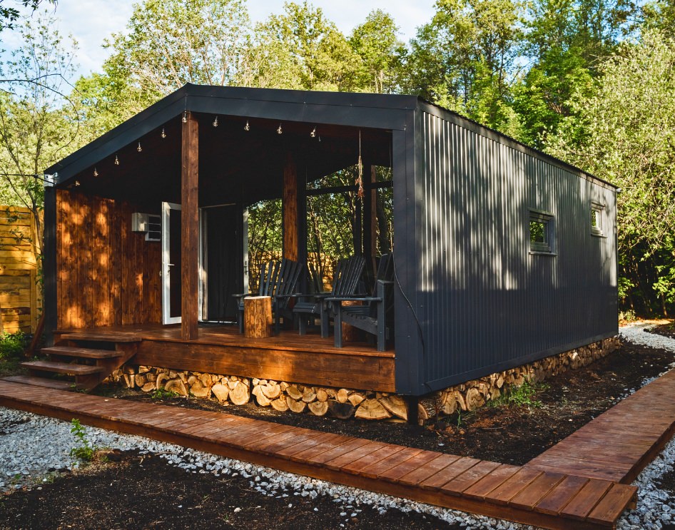 Key Factors to Consider When Choosing Between Manufactured and Stick-Built ADUs - Cozy ADU with wooden accents and a covered patio in a rustic setting.