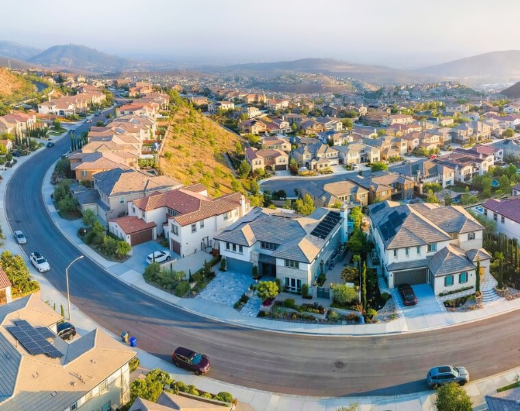 A panoramic aerial view of a San Marcos neighborhood, showcasing modern homes and rolling hills, ideal for ADU construction.