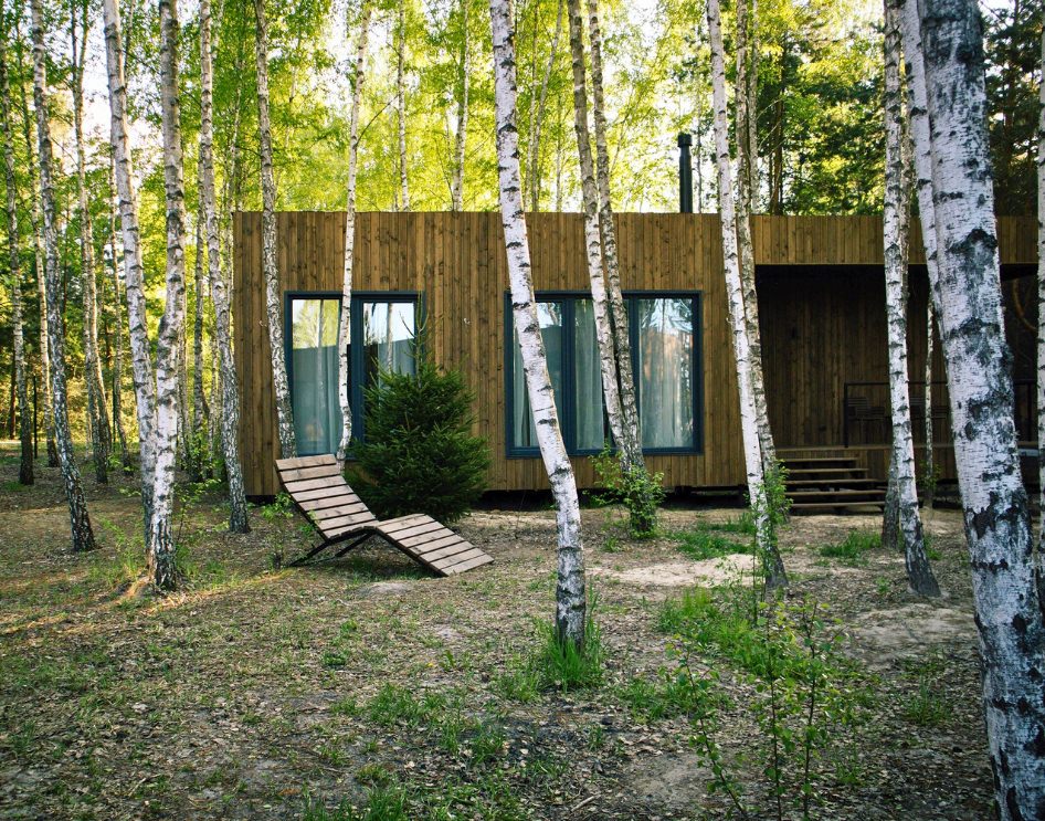 What is a Manufactured ADU - Small white ADU with black metal roof in green backyard.